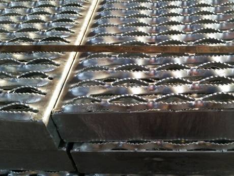 Some diamond-strut safety gratings neatly placed on the ground and fixed by the metal straps.