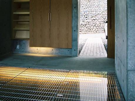 Under a large glass panel, interior decorative steel grating used as floor.