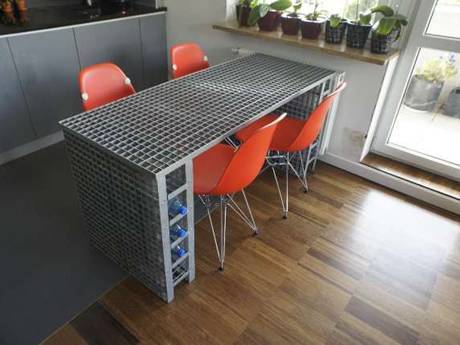 Interior decorative steel grating used as a table with four orange chairs.