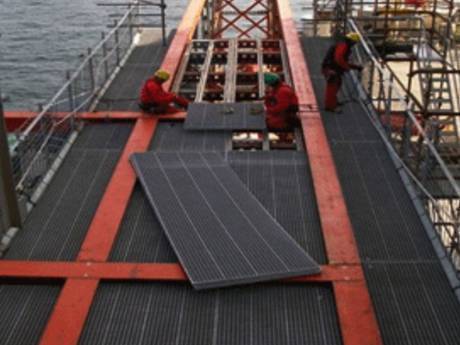 Three workers standing on the offshore platform reinforced grating to work.