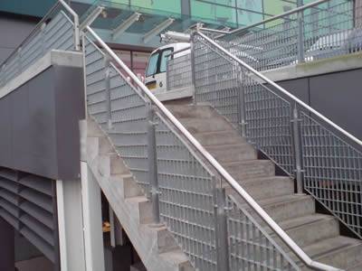 Steel grating infill panels used as stair railings outdoors.