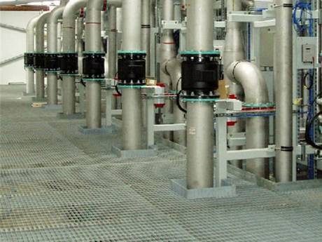 Several pipes standing in the square holes of bar grating pipeline floor.