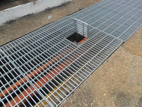 A serrated press-locked steel grating placed on the ground as trench cover.