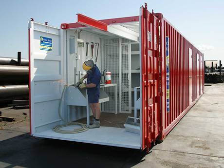 A worker is working in the container that is divided by steel grating partition panels.