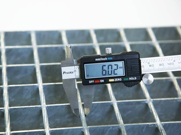 A worker is testing the cross bar size of steel grating