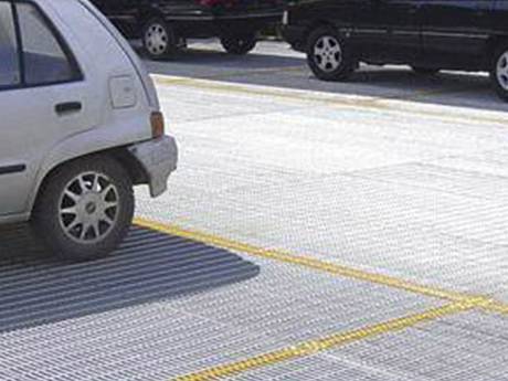 A car is parking on galvanized steel grating floor of open parking.