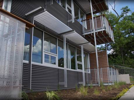 This is a house with steel grating sun shade panels over grassland