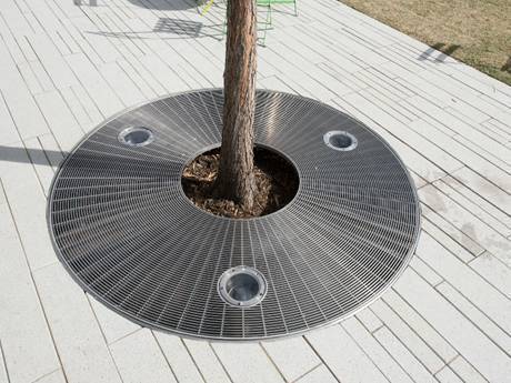 A round tree cover steel grating with a big and three small circles.